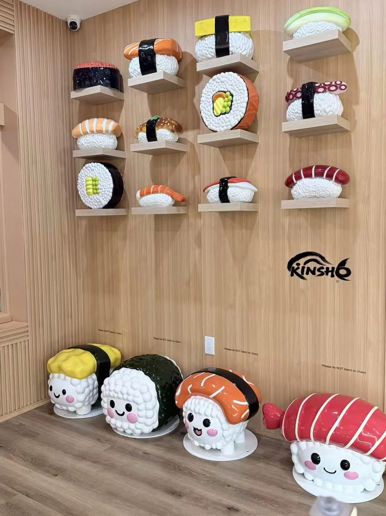 Wall of oversized sushi models and cute sushi character stools at Kinsho restaurant.